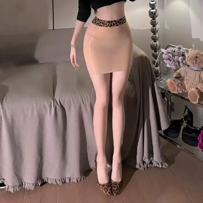 Jupe courte moulante et sexy en tissu soyeux imprimé léopard, effet brillant, avec détails en cuir d